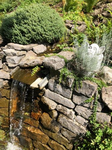 a stone wall with a waterfall in a garden at Apartment Green Elephant in Tettnang