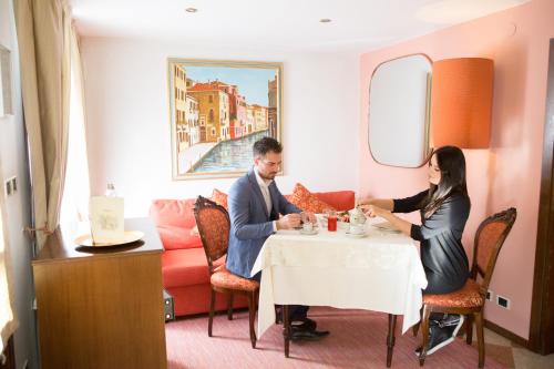 a man and woman sitting at a table in a restaurant at Villa Ducale Hotel & Ristorante in Dolo