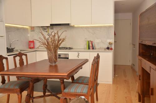a kitchen with a wooden table with chairs and a vase at Jenny and Carmie TOWN HOUSE in Viana do Castelo