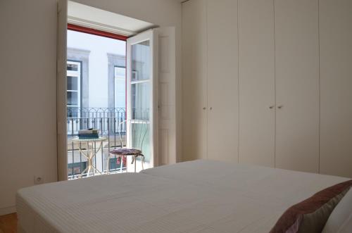 a white bedroom with a bed and a balcony at Jenny and Carmie TOWN HOUSE in Viana do Castelo