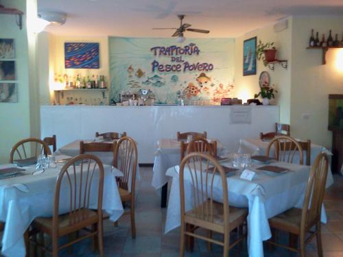 ein Restaurant mit weißen Tischen und Stühlen und einer Theke in der Unterkunft Airone RTA in Orbetello