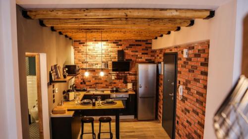 a kitchen with a brick wall and a counter with stools at LM Luxury Central Loft in Larisa