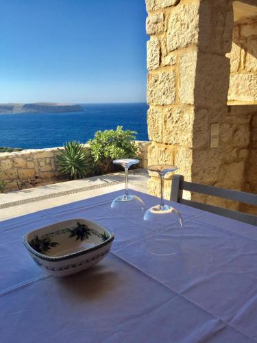 a table with two glasses and a bowl on a table with the ocean at Stonehouse villas with breathtaking view in Sitia