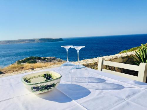 a table with two wine glasses and a bowl on it at Stonehouse villas with breathtaking view in Sitia