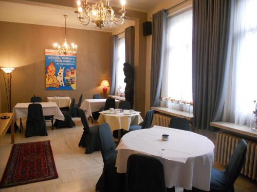 een restaurant met witte tafels, stoelen en ramen bij Hotel Ten Putte in Gistel