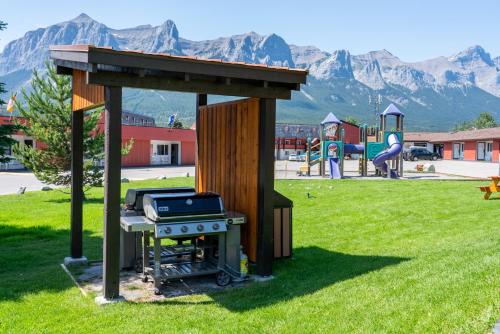 a barbecue grill in a park with mountains in the background at Rocky Mountain Ski Lodge in Canmore