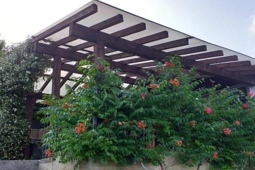 a wooden pergola over some plants with red flowers at La Casina nella Valle in Serina