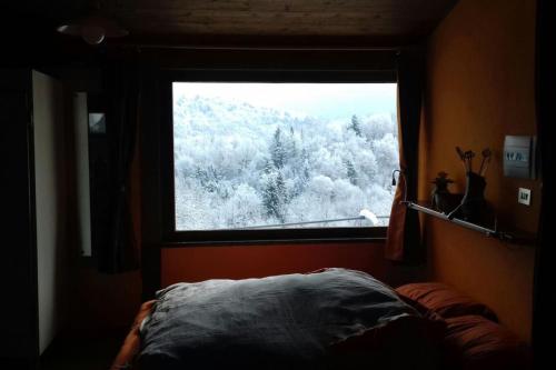 a bedroom with a window with a view of snow covered trees at La Casina nella Valle in Serina