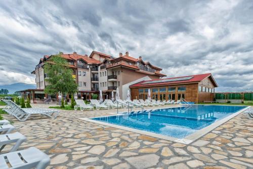 a resort with a swimming pool and chairs and a building at Thermal Hotel Seven Seasons in Bansko