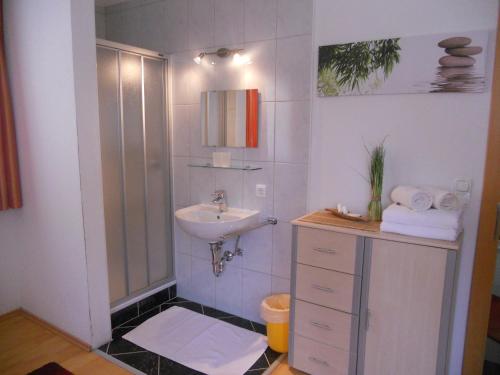 a white bathroom with a sink and a shower at Apart Bella Cascata in Kappl
