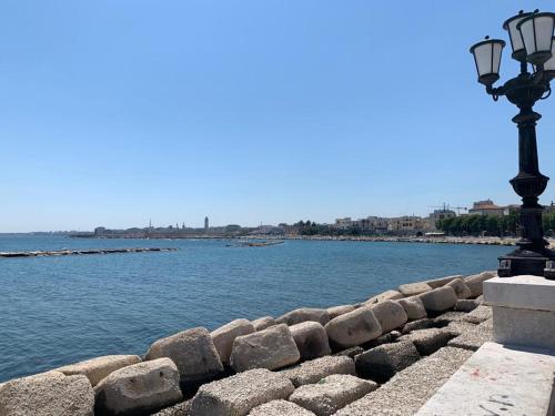 Un muro de piedra con una farola junto al agua. en MEA HOUSE AND ROOM 2019, en Bari