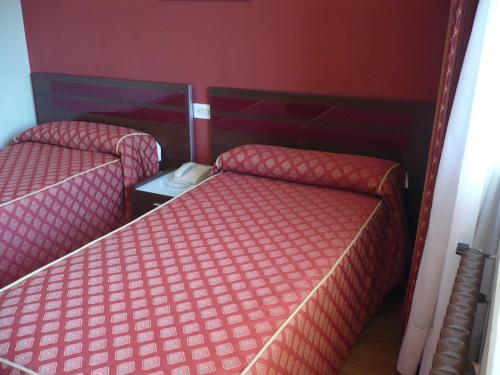 two beds in a room with red walls at Las Islas in Vilaboa