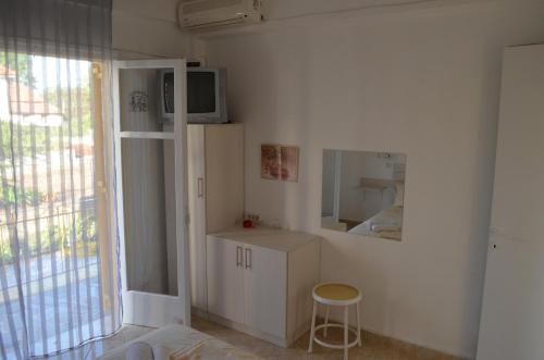 Cet appartement comprend une chambre dotée d'une télévision et d'un tabouret. dans l'établissement Yellow House, à Kavos
