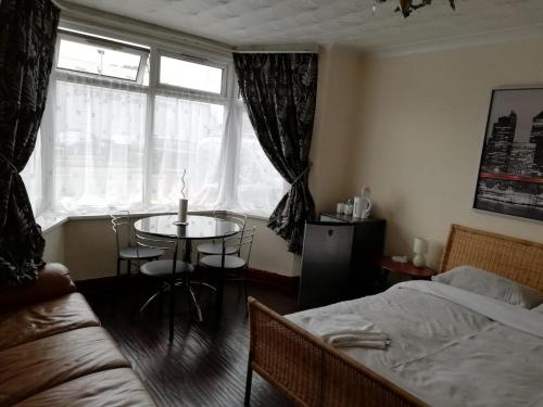 a bedroom with a bed and a table and a window at Cozy Guest House in Luton