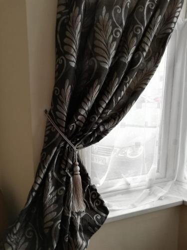 a window with a black and white curtain at Cozy Guest House in Luton