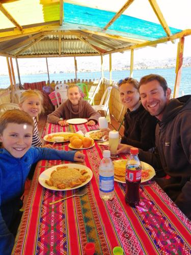 a group of people sitting at a table eating food at Urosfood & Titiqaqa Lodge in Uros