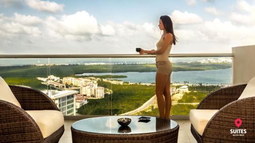 a woman standing on a balcony looking out at the water at Suites Malecon Cancun in Cancún