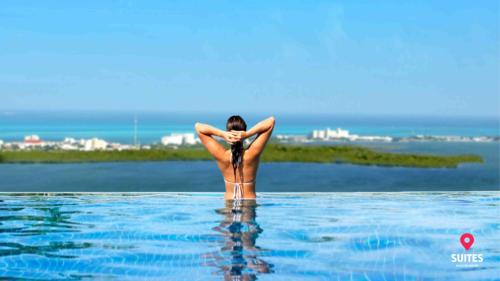 a woman is standing in the water in a swimming pool at Suites Malecon Cancun in Cancún