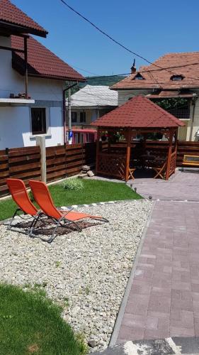 two chairs in a yard with a gazebo at Căsuța cu Izvor in Călimăneşti