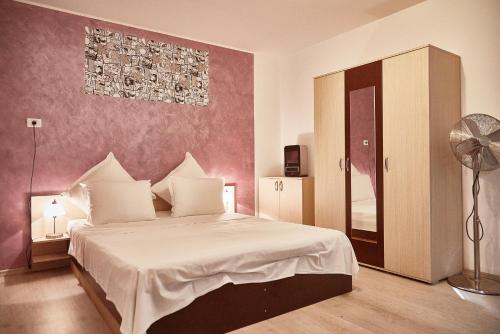 a bedroom with a white bed and a pink wall at Gabizz Apartments in Constanţa