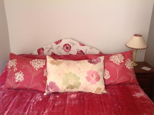 a bed with red sheets and two pillows on it at The Bittern in Blakeney