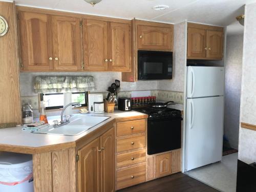a kitchen with wooden cabinets and a white refrigerator at Garden Bay Hideaway - Glamping & RV in Garden Bay