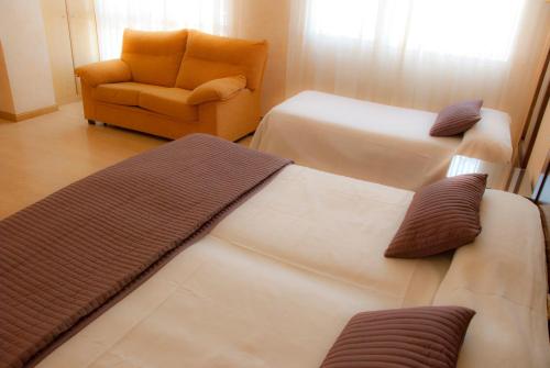 a hotel room with two beds and a chair at Abadía Burgos Camino Santiago in Burgos