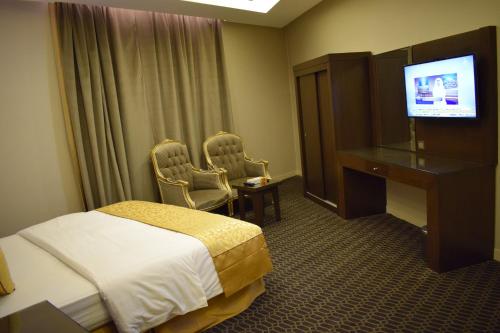 a hotel room with a bed and a desk and a television at شقق منازل الدانة للشقق المخدومة in Abha