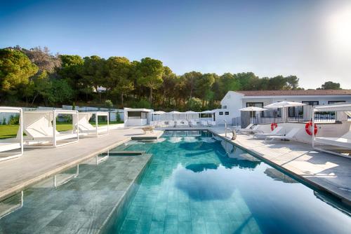 a large swimming pool with chairs and a building at Hotel Eetu - Adults Only in Begur