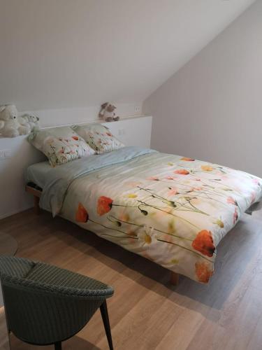 ein Bett mit einer Bettdecke und einem Stuhl in einem Schlafzimmer in der Unterkunft Luxueus duplex appartement aan zee in Koksijde
