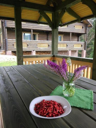 a bowl of berries on a table with a vase of flowers at GUTSULWOOD in Yablunytsya