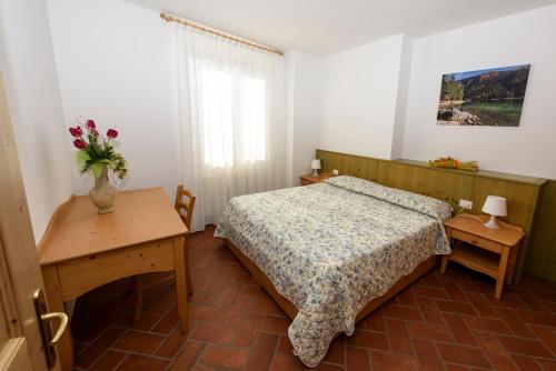 a bedroom with a bed and a table with a vase of flowers at Agritur La Pieve in Taio