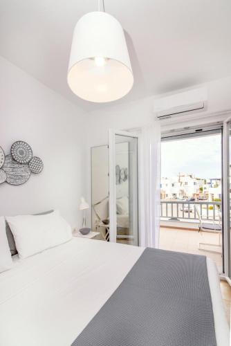 a white bedroom with a bed and a large window at IKIES TINOS A and B in Tinos