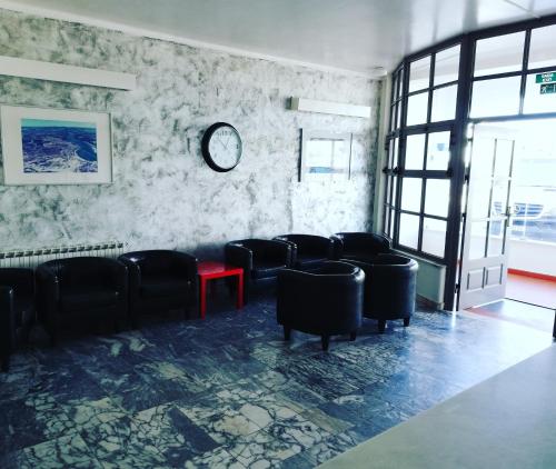 a waiting room with chairs and a clock on the wall at Hotel Eira Da Pedra in Vila Nova de Milfontes