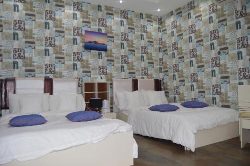 2 Betten mit Kissen in einem Zimmer mit einer Wand in der Unterkunft Happiness Farm in Hatta