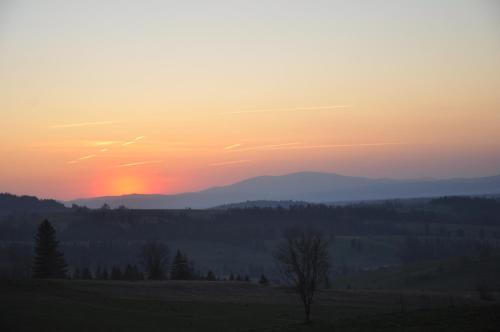 a sunset over a field with mountains in the background at Apartamenty Dwupoziomowe Na Dwa Widoki z Jacuzzi & Sauna in Zakopane
