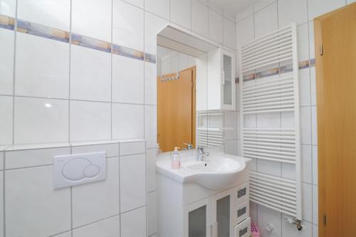 a white bathroom with a sink and a mirror at Nordseesonne Greetsiel in Krummhörn