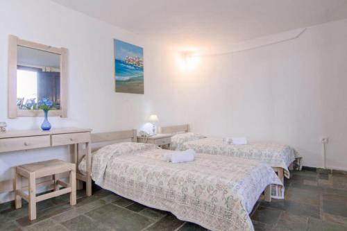 a room with two beds and a desk and a mirror at Paros Eden Park in Parikia