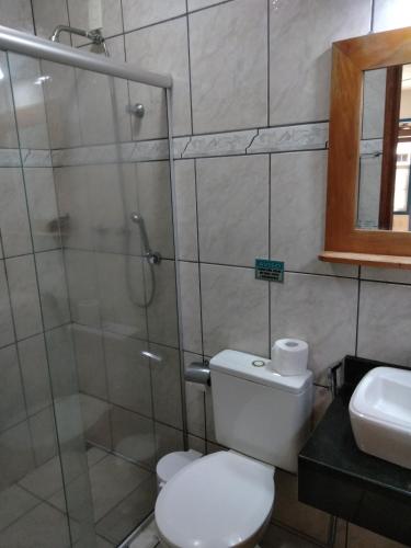 a bathroom with a toilet and a glass shower at Pousada Amaryllis in Tiradentes