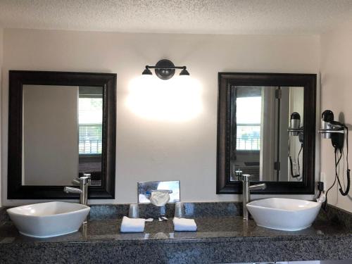 two sinks in a bathroom with two mirrors at Sun Coast Inn in Englewood