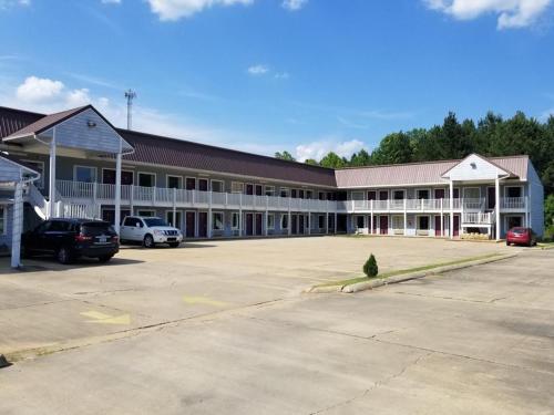 a large building with cars parked in a parking lot at Oak Tree Inn Eupora in Eupora