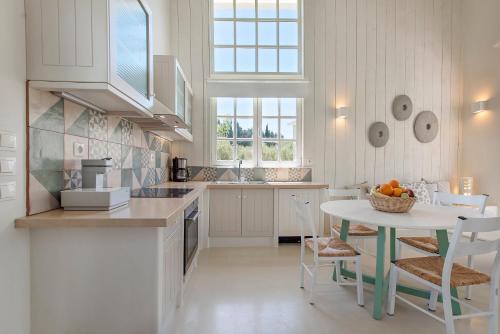 a white kitchen with a table and chairs in it at Ta Spitakia in Kos Town