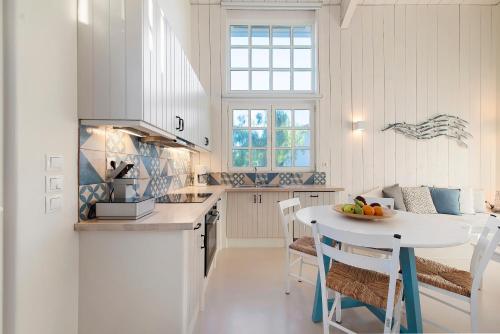 a white kitchen with a white table and chairs at Ta Spitakia in Kos Town