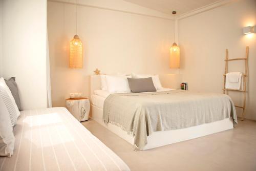 a white bedroom with a white bed and two lights at Ta Spitakia in Kos Town