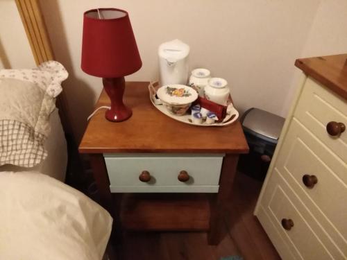 Catherine's Lair A Quiet peaceful Homestay في ويستبورت: طاولة بجانب السرير مع مصباح وصحن من الطعام عليه