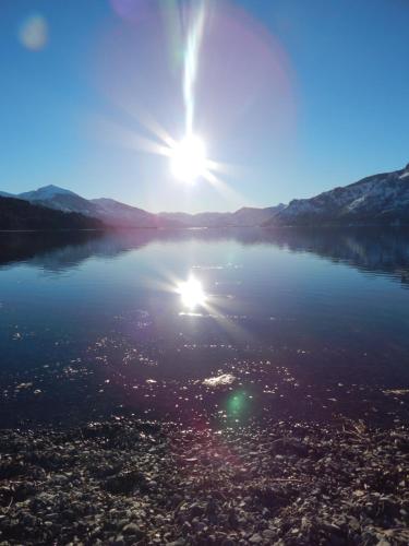 a large body of water with the sun in the sky at Cabañas Wenuray in Villa Meliquina