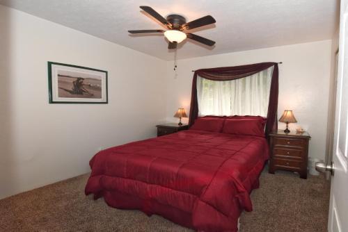 a bedroom with a red bed with a ceiling fan at Humble Home in Hawaii in Ainaloa