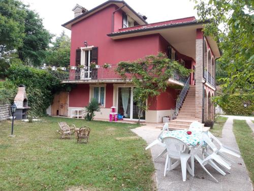 a house with a table and chairs in the yard at Villa per gruppi fino a 20 persone, con piscina privata, camino e grande giardino nelle colline marchigiane in Pian di Mulino