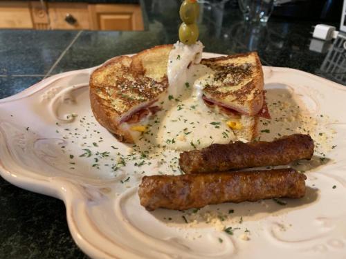 a plate of food with a sandwich and sausage at Peace & Plenty Inn Bed and Breakfast Downtown St Augustine-Adults Only in Saint Augustine