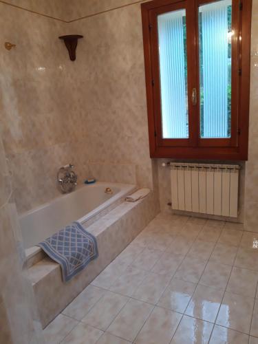 a bathroom with a bath tub and a window at Villa per gruppi fino a 20 persone, con piscina privata, camino e grande giardino nelle colline marchigiane in Pian di Mulino